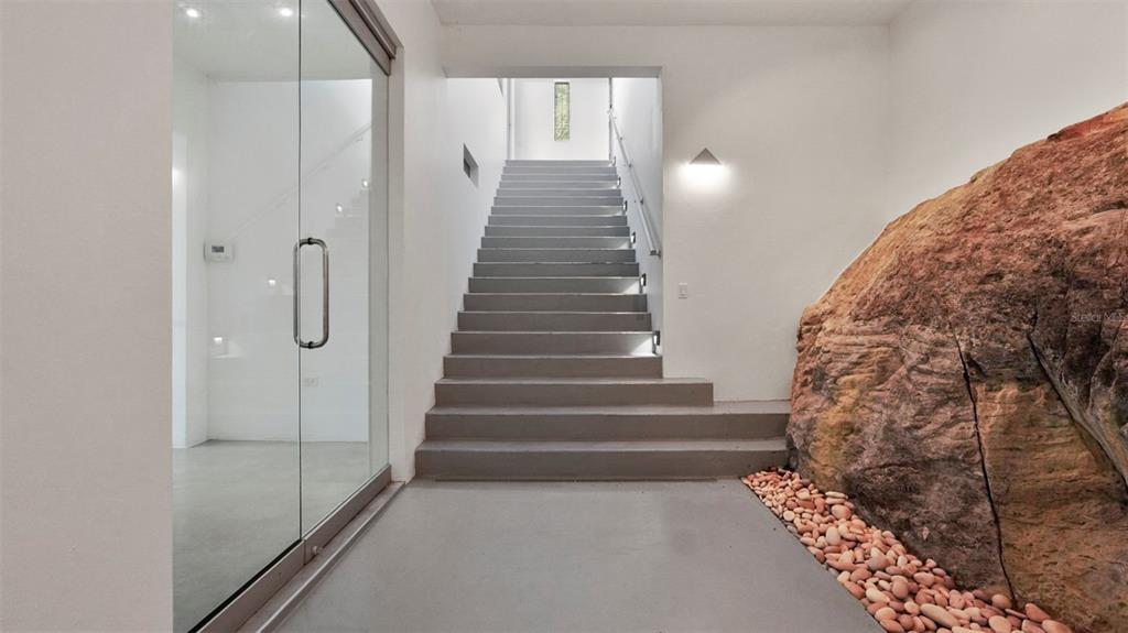 A modern interior staircase features a large natural rock formation and a glass-enclosed room — km 16.5 PR-15, CAYEY, PR
