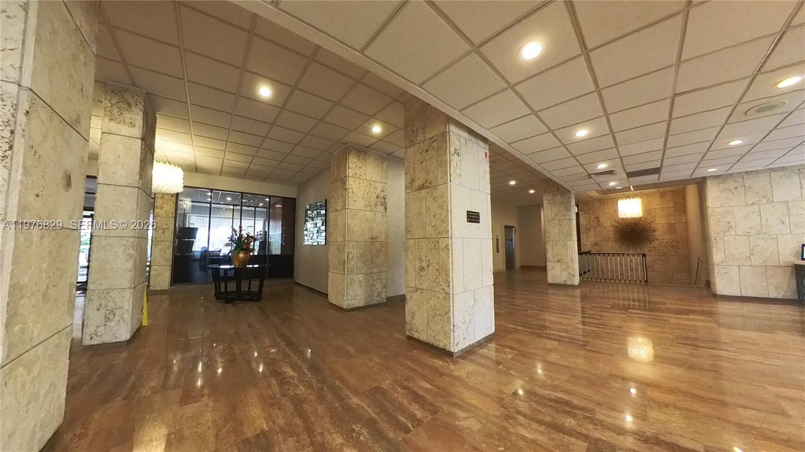 A spacious lobby features polished stone floors, tiled columns, and a drop ceiling with recessed lighting — 1965 S Ocean Dr # 7E, Hallandale Beach FL 33009, HALLANDALE BEACH, FL