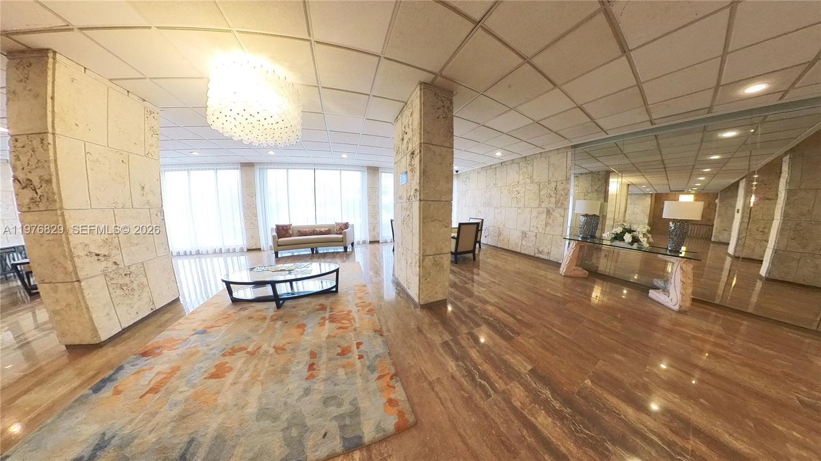 A lobby area features stone-tiled walls, a polished floor, and a large crystal chandelier — 1965 S Ocean Dr # 7E, Hallandale Beach FL 33009, HALLANDALE BEACH, FL
