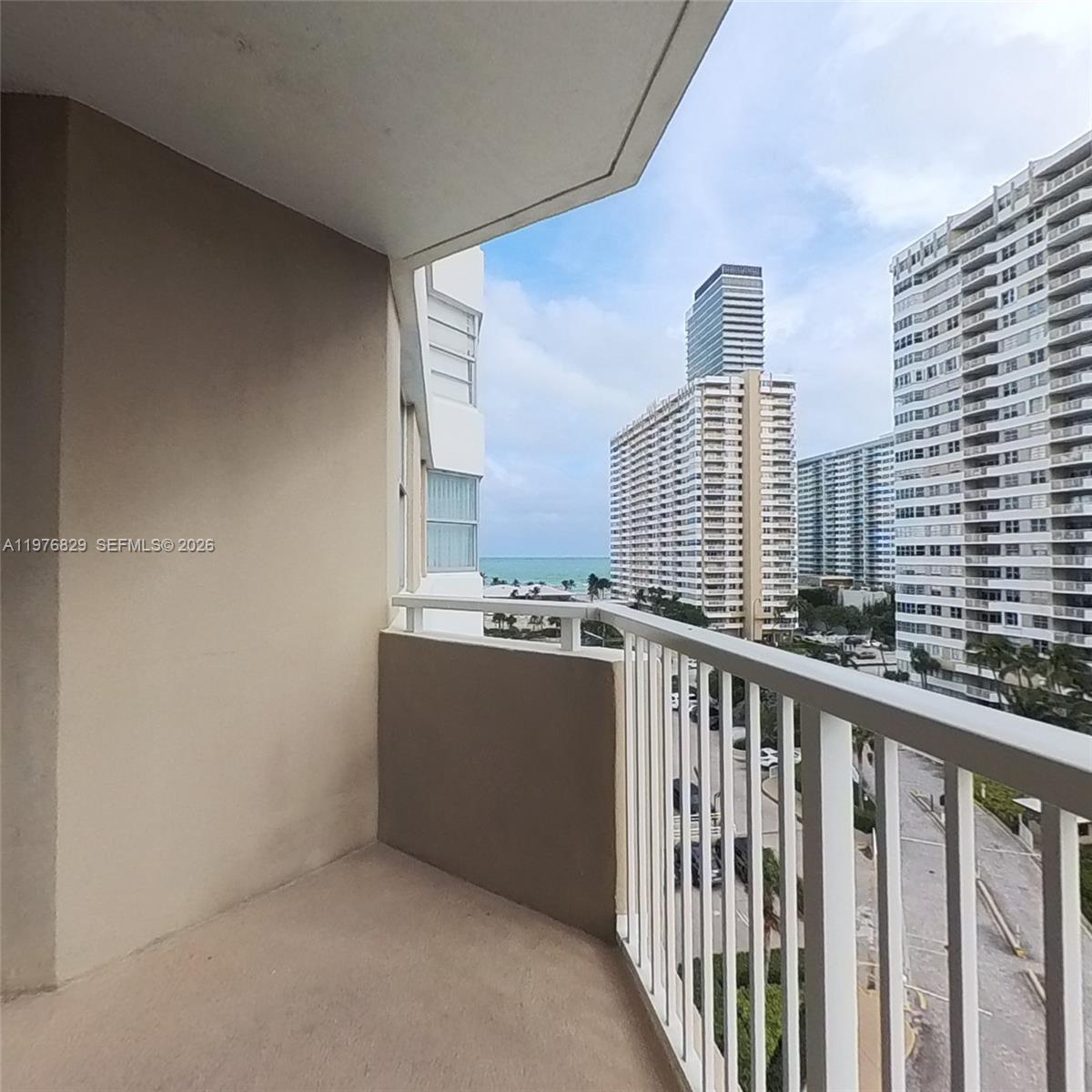 A balcony with a white railing overlooks a coastal city and the ocean — 1965 S Ocean Dr # 7E, Hallandale Beach FL 33009, HALLANDALE BEACH, FL