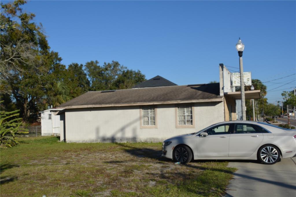 A single-story, light-colored building with a dark roof sits next to a parked silver sedan — 1006 S HISTORIC GOLDSBORO, SANFORD, FL