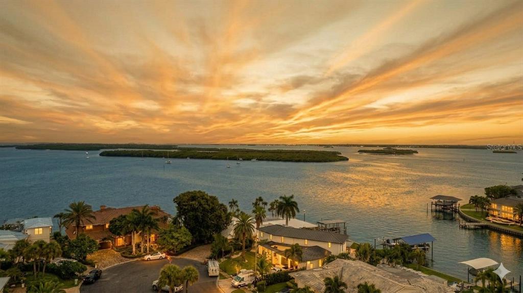 An aerial view of waterfront homes at sunset with a large bay and mangrove islands — 891 ISLAND WAY, CLEARWATER BEACH, FL