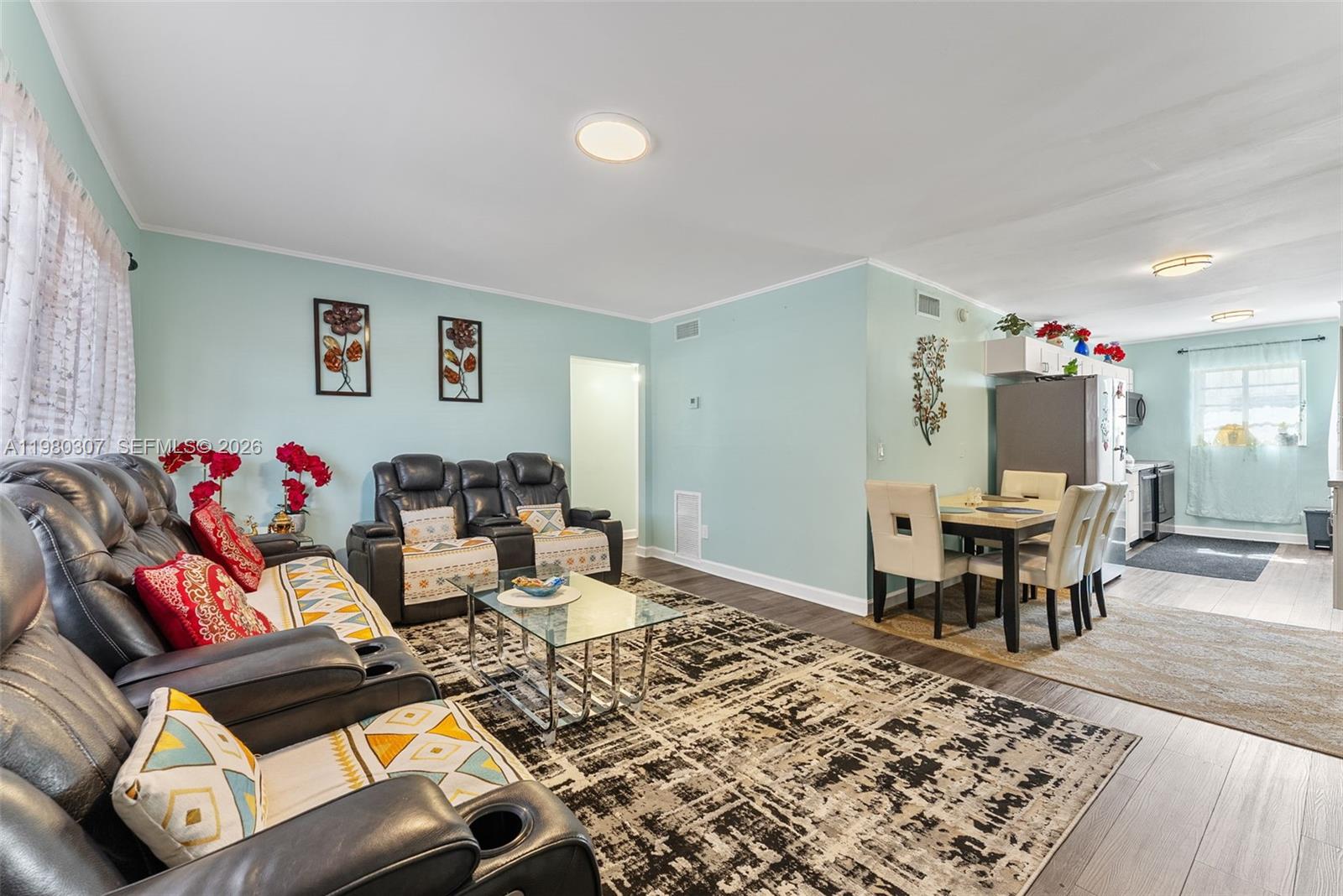A living room and dining area feature light blue walls, dark furniture, and area rugs — 7331 Gary Ave # 206, Miami Beach FL 33141, MIAMI BEACH, FL
