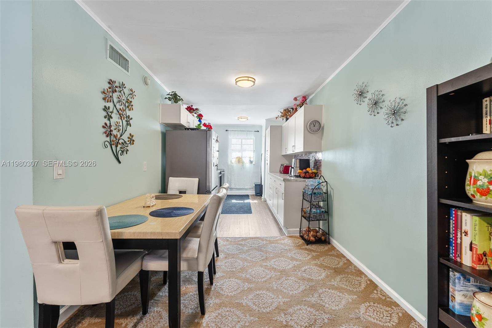 This dining area and kitchen features light blue walls, a patterned rug, and white cabinetry — 7331 Gary Ave # 206, Miami Beach FL 33141, MIAMI BEACH, FL
