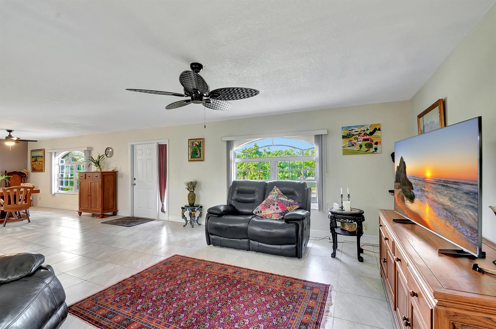 A living room features tile floors, a ceiling fan, a leather loveseat, and a television — 3446 Cabbage Palm Way, Loxahatchee FL 33470, LOXAHATCHEE, FL