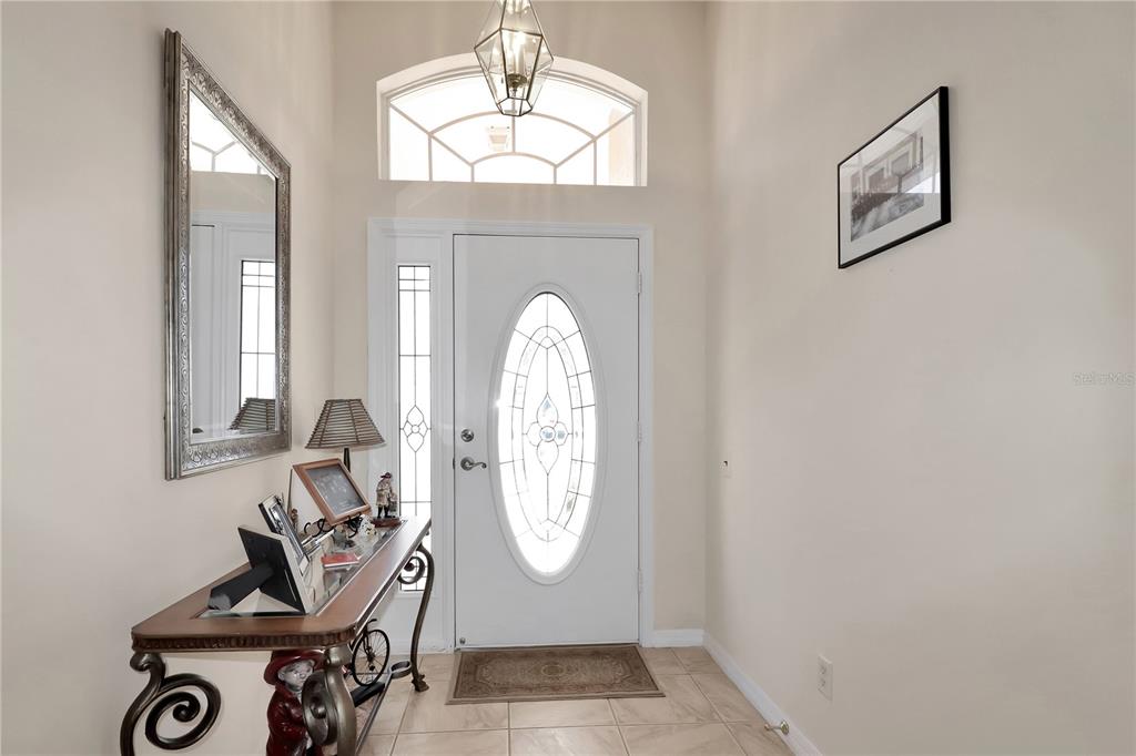 An entryway features a white front door with a glass insert, tile flooring, and a mirror — 20751 QUEEN ALEXANDRA DRIVE, LEESBURG, FL