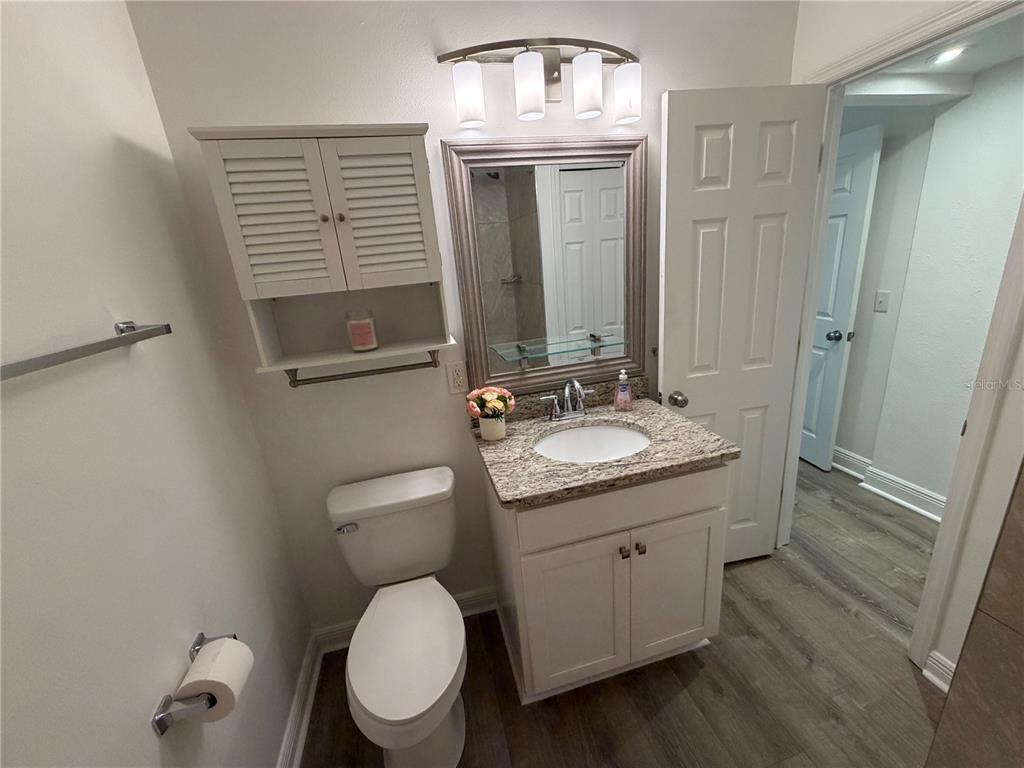 A bathroom features a white vanity with a granite countertop, a toilet, and wall cabinetry — 904 KENSINGTON DRIVE, COCOA, FL