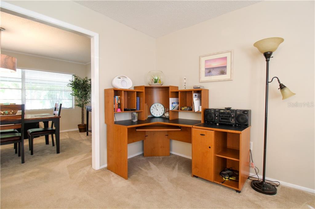 A corner desk with hutch sits in a carpeted room next to a floor lamp — 2806 TAUNTON DRIVE W, BRADENTON, FL