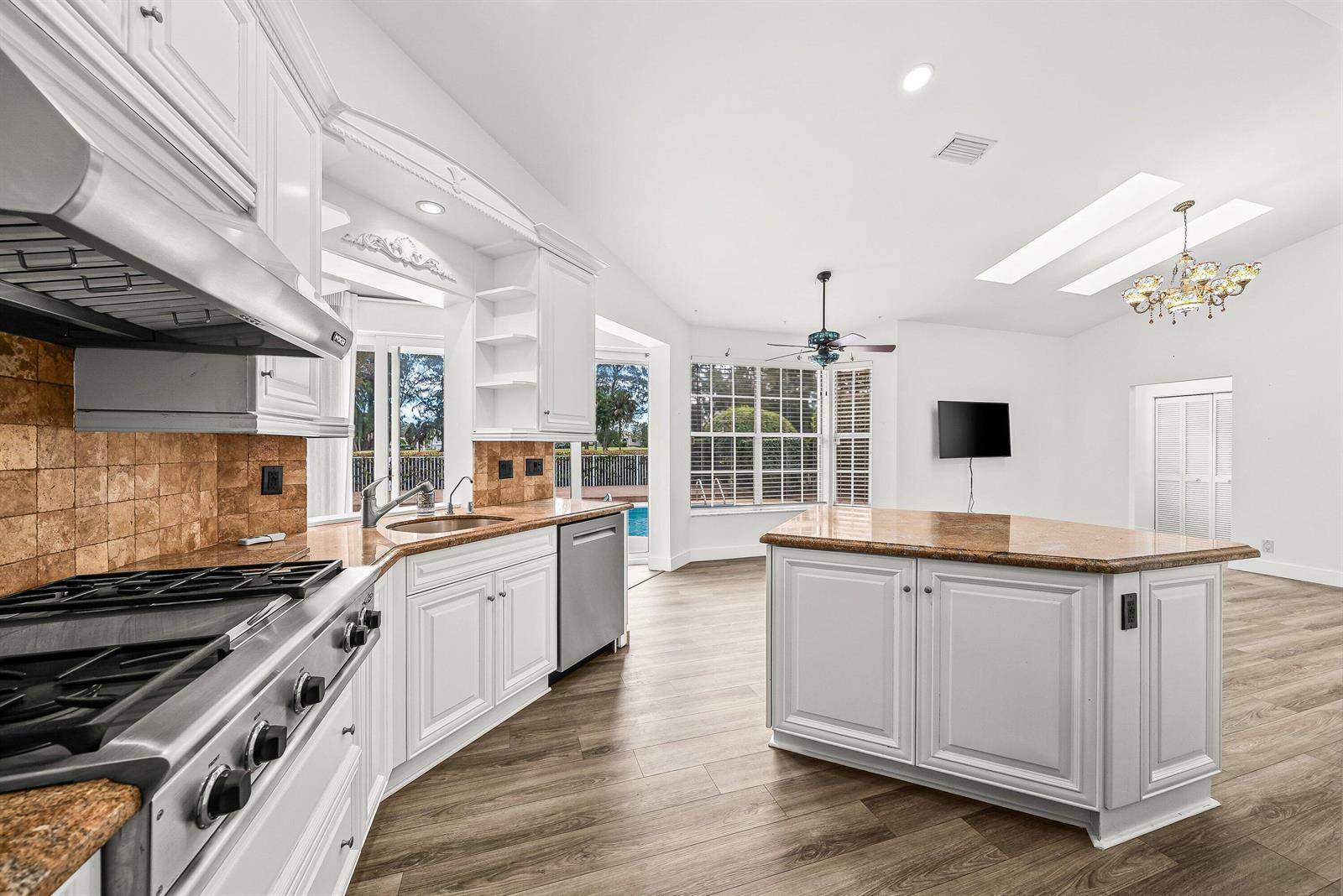 A kitchen with white cabinets, granite countertops, stainless steel appliances, and wood-look flooring — 230 Eagleton Estate Boulevard, Palm Beach Gardens FL 33418, PALM BEACH GARDENS, FL