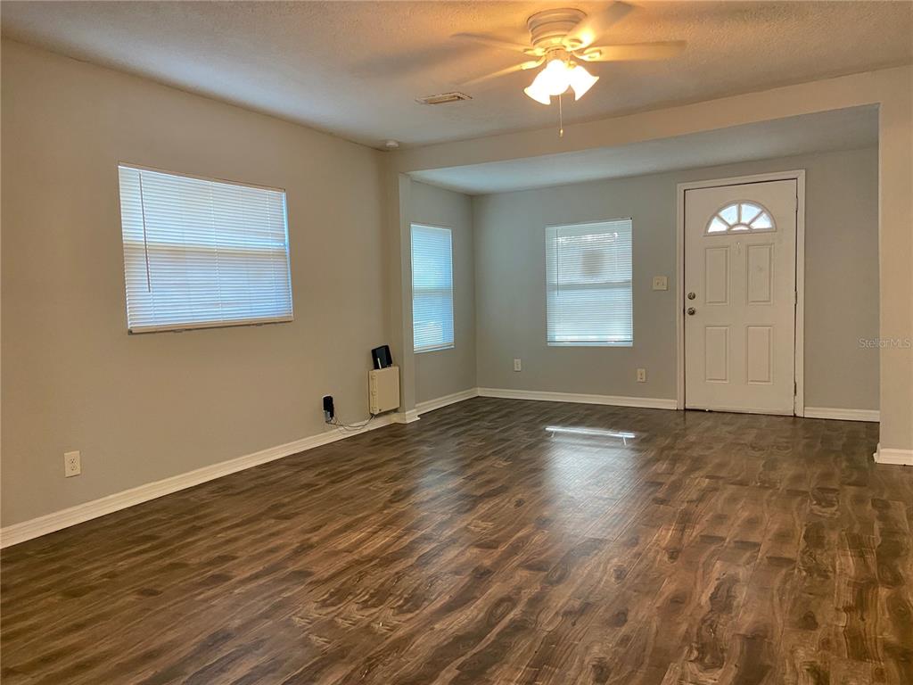 An empty living room features light gray walls, wood-look flooring, and a ceiling fan — 8105 N 12TH STREET, TAMPA, FL
