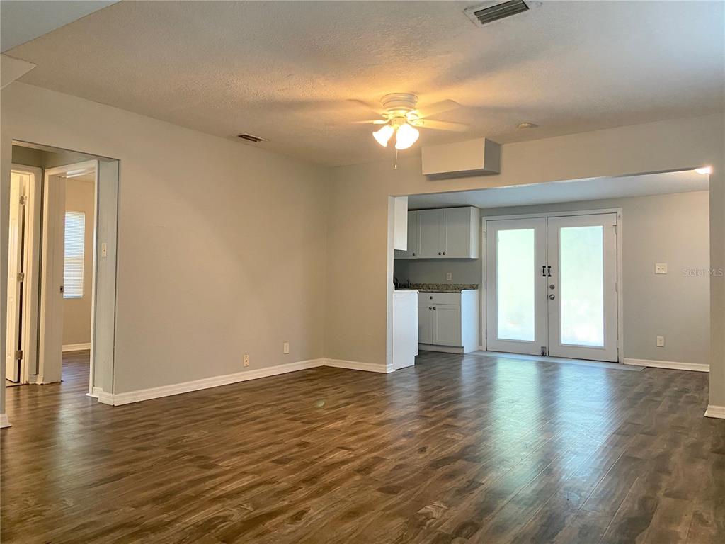 An open-concept living area features wood-look flooring, light gray walls, and a kitchen beyond — 8105 N 12TH STREET, TAMPA, FL