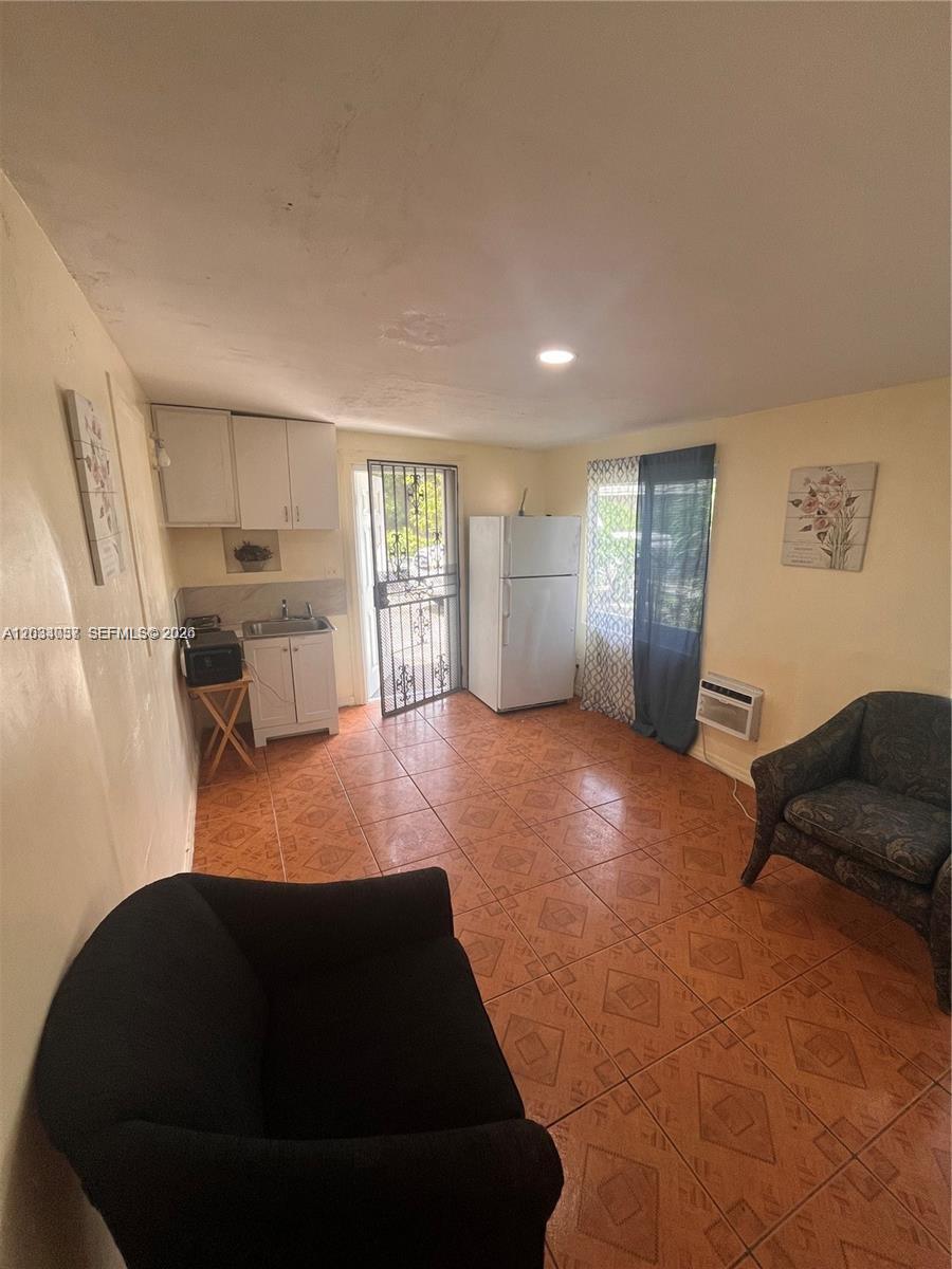 A small kitchen area with white cabinets, a refrigerator, and tiled floors — 13215 NW 19th Ave # 1, Miami FL 33167, MIAMI, FL