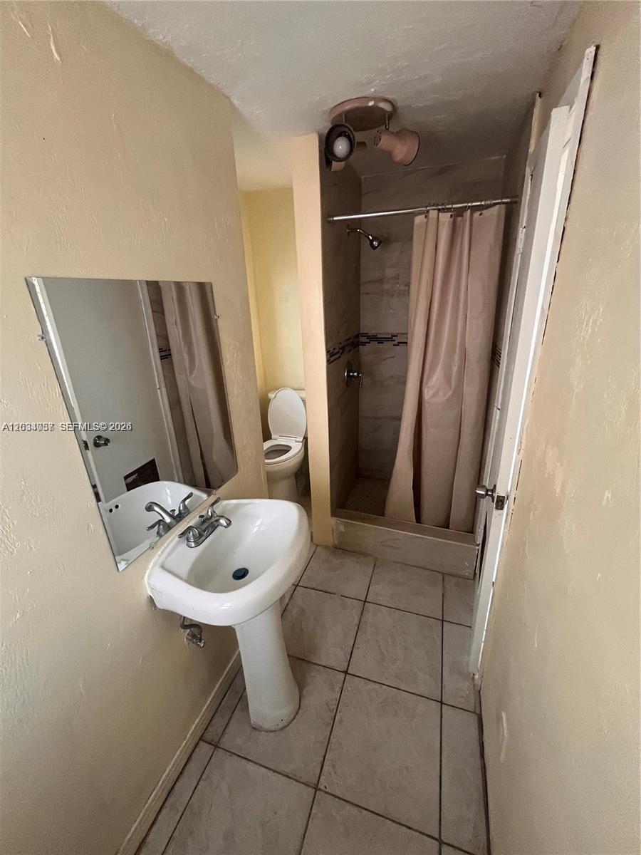 This bathroom features a pedestal sink, a mirror, a toilet, and a tiled shower stall — 13215 NW 19th Ave # 1, Miami FL 33167, MIAMI, FL