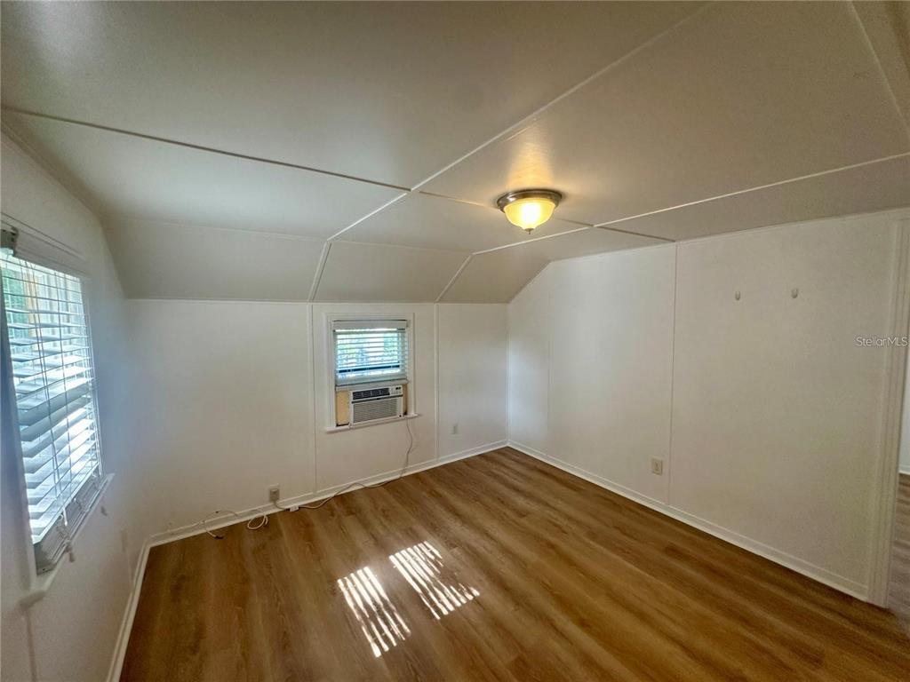 An empty room with white paneled walls, a sloped ceiling, and wood-look flooring — 15 1/2 4TH STREET N, LAKE WALES, FL