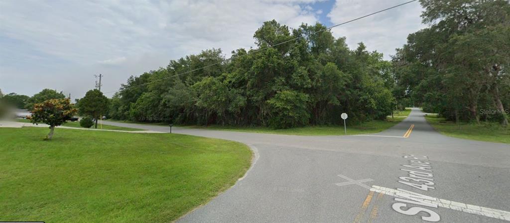 A view of a wooded corner lot at the intersection of two paved roads — LOT 20 SW 132ND STREET, OCALA, FL