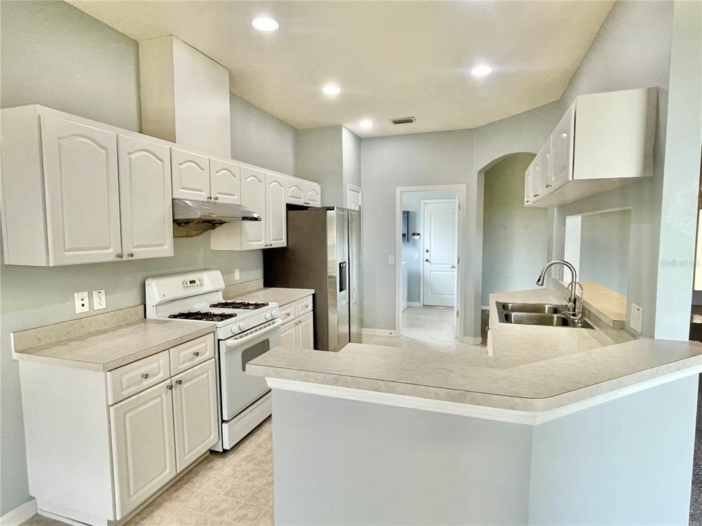 A kitchen features white cabinets, stainless steel appliances, a breakfast bar, and light countertops — 24652 PORTOFINO DRIVE, LUTZ, FL