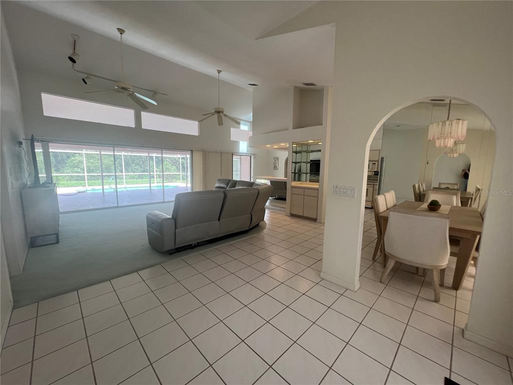 A living room with vaulted ceilings and tile floors opens to a dining area — 2300 MAURITANIA ROAD, PUNTA GORDA, FL