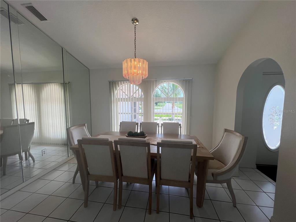 A dining room features a wooden table, six upholstered chairs, a chandelier, and mirrored walls — 2300 MAURITANIA ROAD, PUNTA GORDA, FL