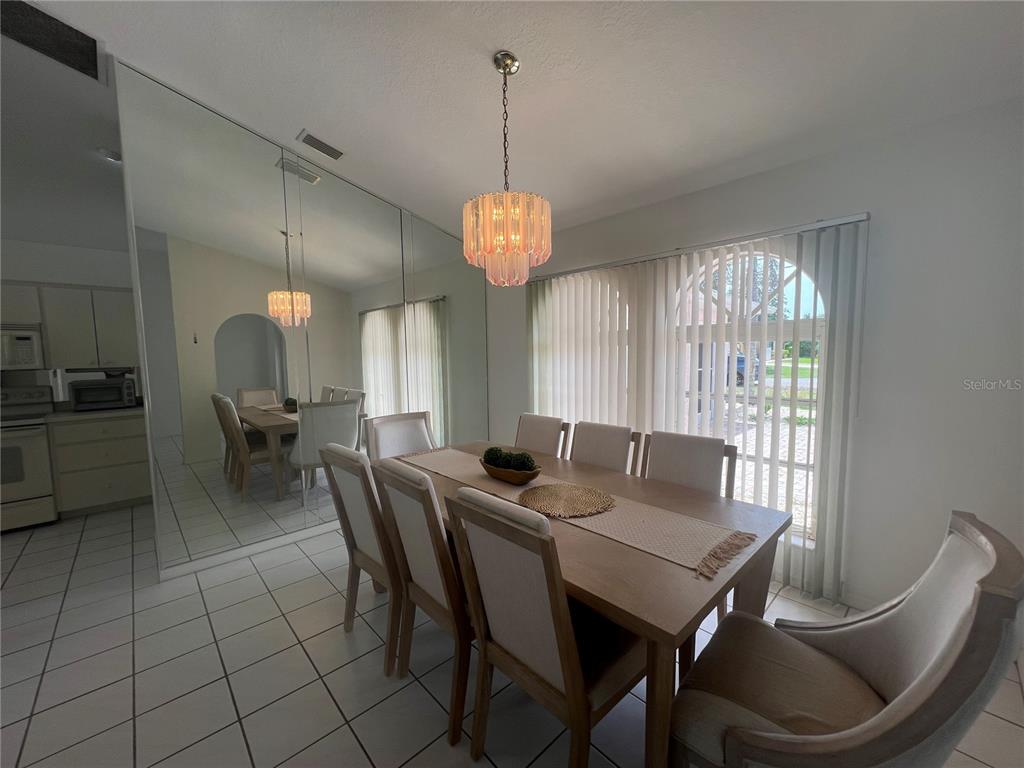 A dining room features a wooden table, upholstered chairs, a chandelier, and a mirrored wall — 2300 MAURITANIA ROAD, PUNTA GORDA, FL