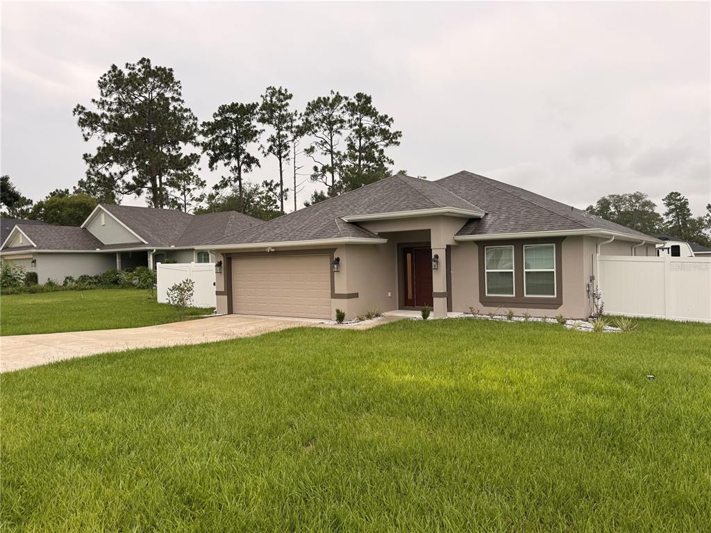A red front door with sidelights is set within a covered entryway of a house — 8797 SE 161ST PLACE, SUMMERFIELD, FL