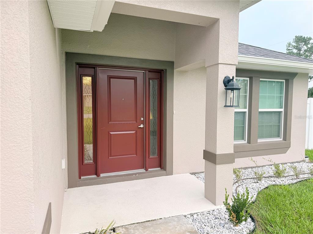 An entryway leads into a dining area with light wood-look tile floors and two chandeliers — 8797 SE 161ST PLACE, SUMMERFIELD, FL