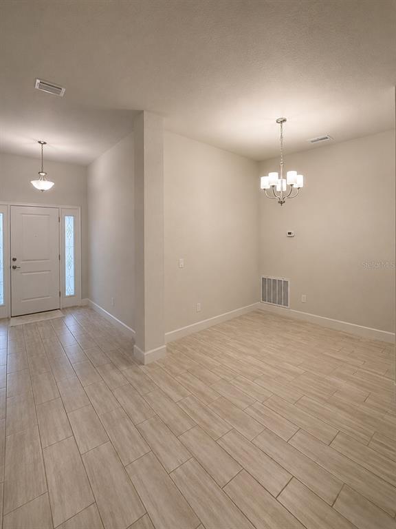 A kitchen with white cabinets, brown patterned countertops, and light-colored tile flooring — 8797 SE 161ST PLACE, SUMMERFIELD, FL