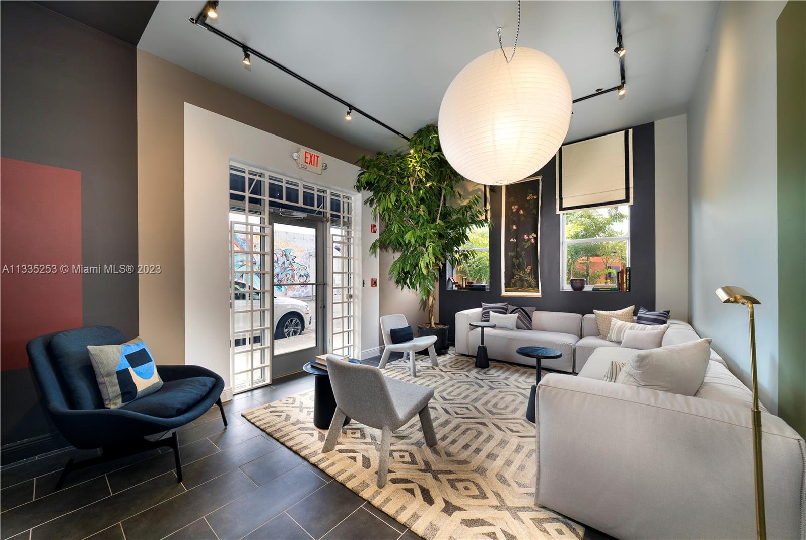 A modern lounge area features a large white pendant light, sectional sofa, and patterned rug — 804 NW 21st Ter, Miami FL 33127, MIAMI, FL