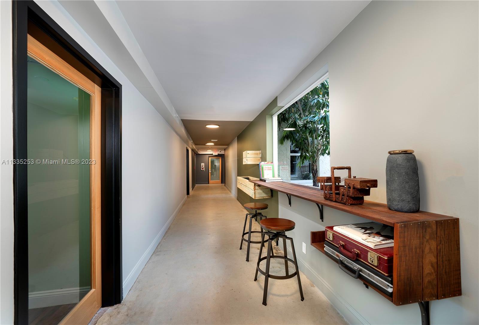 A hallway features a wooden bar counter with stools, a window, and concrete flooring — 804 NW 21st Ter, Miami FL 33127, MIAMI, FL