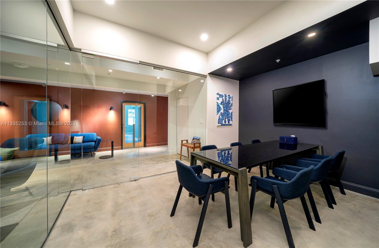 A modern conference room features a glass wall, dark blue accent wall, and concrete flooring — 804 NW 21st Ter, Miami FL 33127, MIAMI, FL