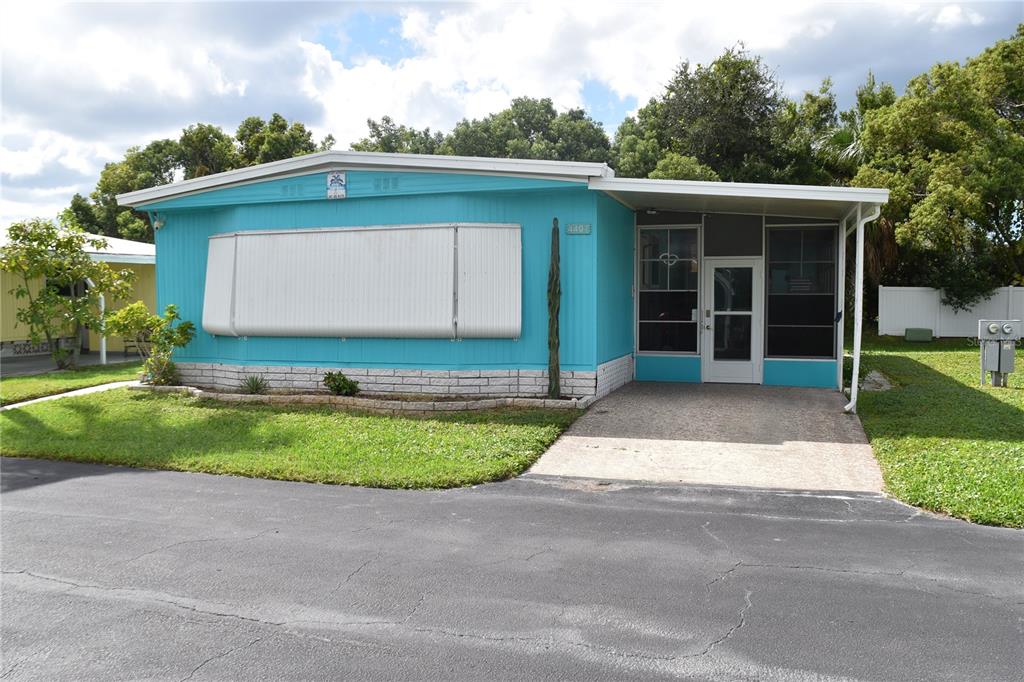 A turquoise mobile home features a white awning over a large window and a carport — 4407 TUCKER SQUARE, NEW PORT RICHEY, FL