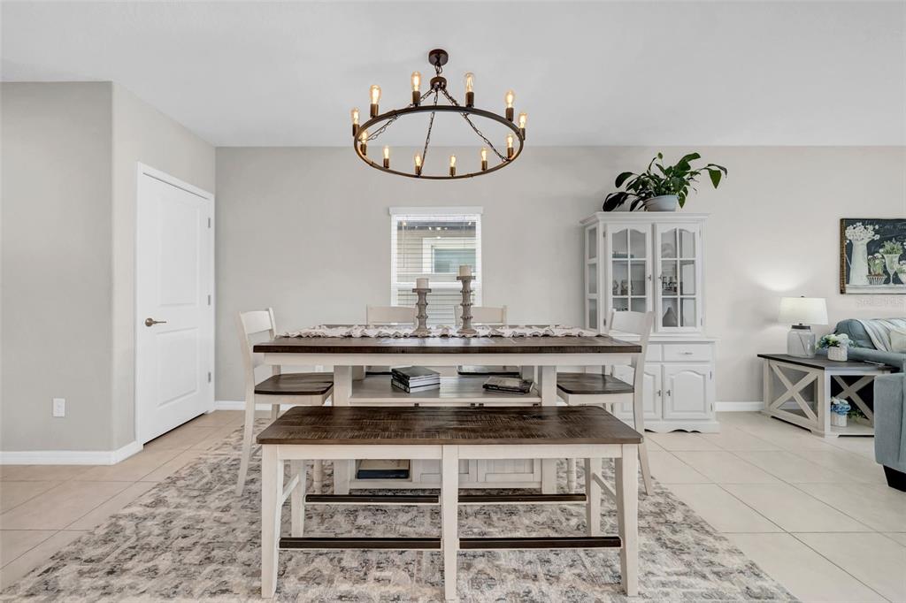 A dining room features a wooden table with a bench, chairs, and a wagon-wheel chandelier — 31440 BARREL WAVE WAY, WESLEY CHAPEL, FL