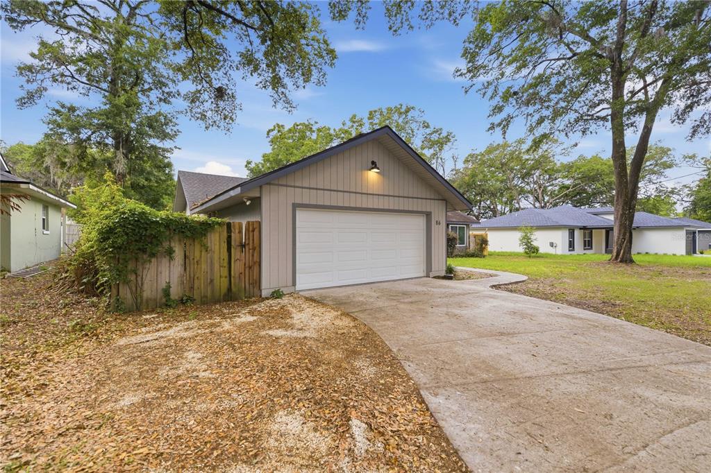 A detached garage with a white door, light-colored siding, and a concrete driveway — 86 PECAN DRIVE, OCALA, FL