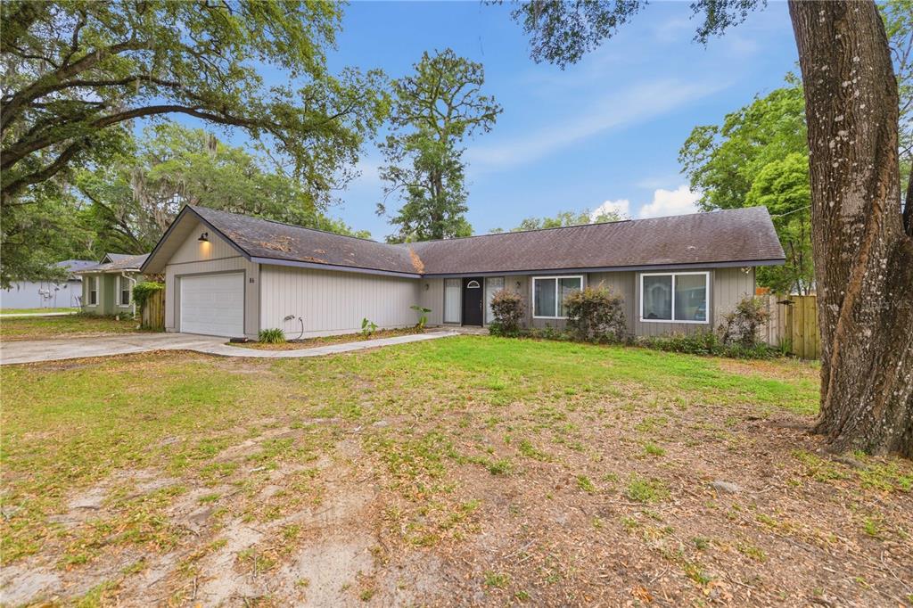 A single-story house with a gray exterior, a two-car garage, and a large front yard — 86 PECAN DRIVE, OCALA, FL