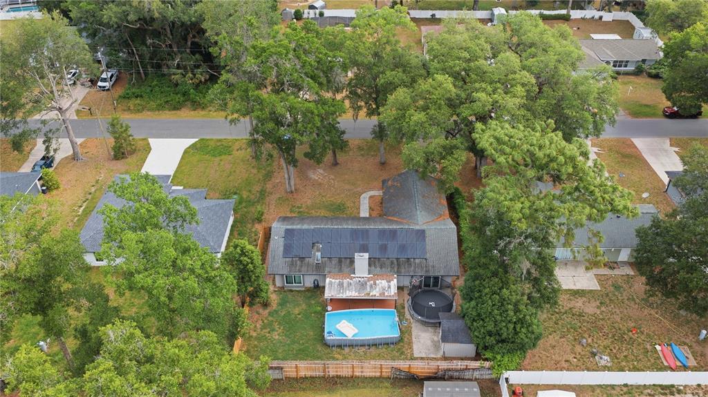 An aerial view shows a house with solar panels, a backyard pool, and a trampoline — 86 PECAN DRIVE, OCALA, FL