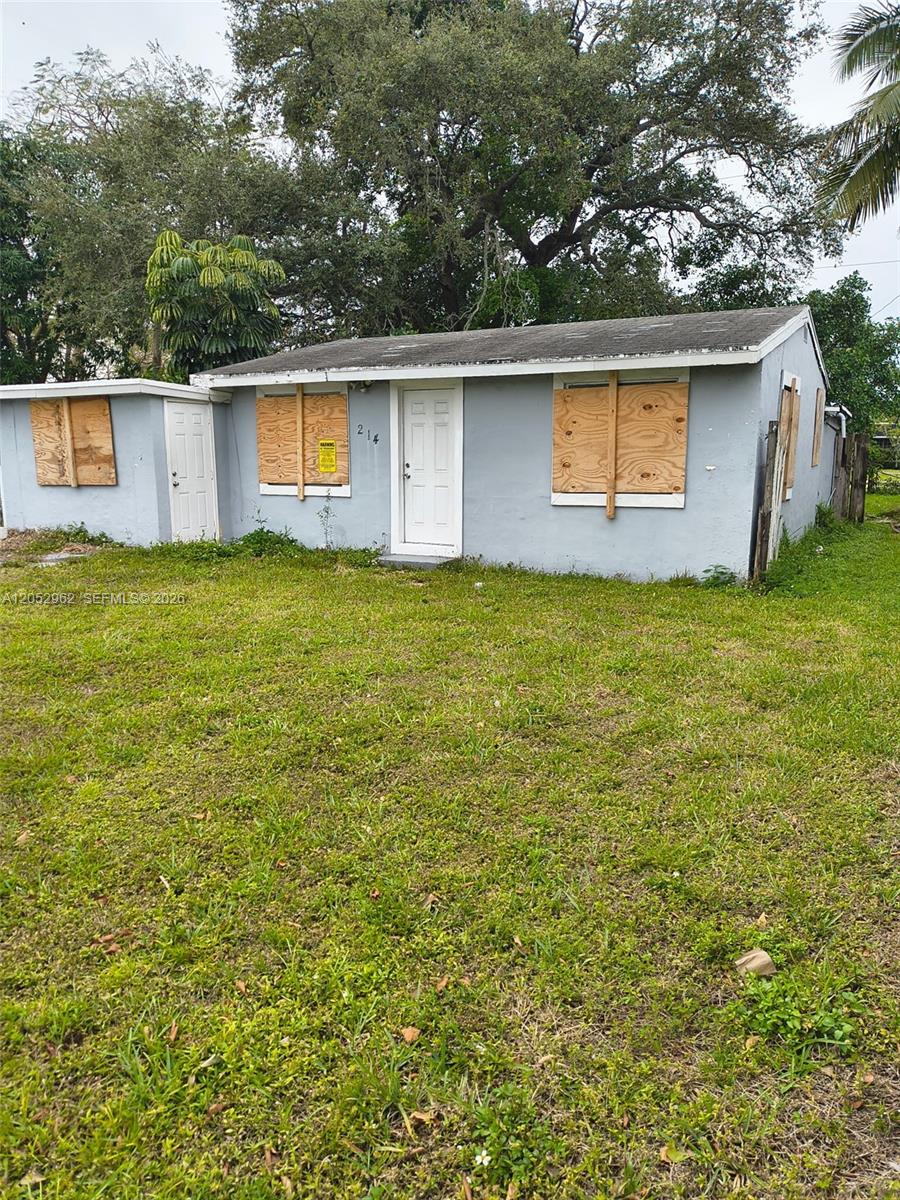 A single-story house with boarded-up windows and a white front door sits on a grassy lot — 214 N 61st Ter, Hollywood FL 33024, HOLLYWOOD, FL
