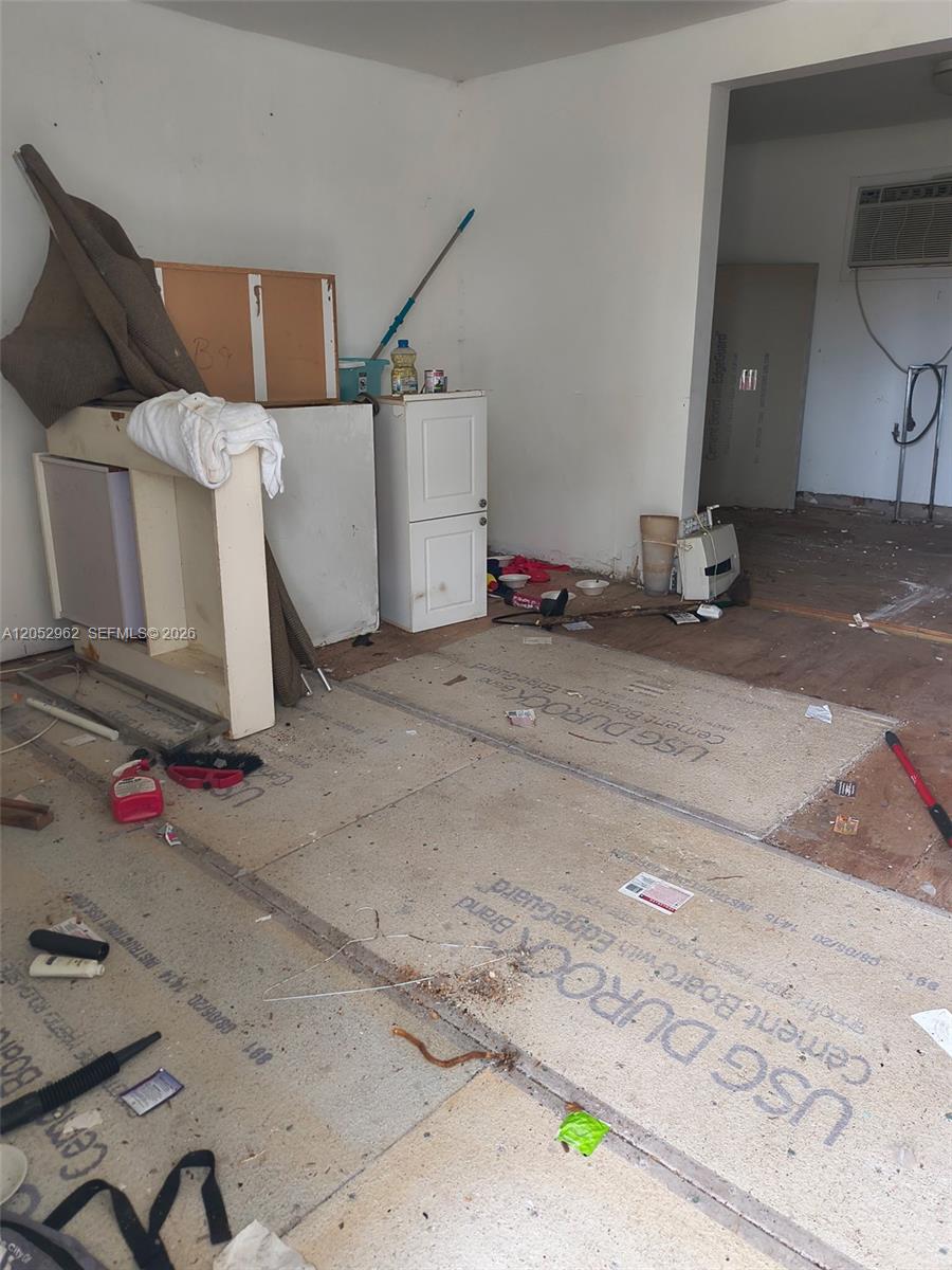 An unfinished room features exposed cement board subflooring, scattered construction debris, and some storage cabinets — 214 N 61st Ter, Hollywood FL 33024, HOLLYWOOD, FL