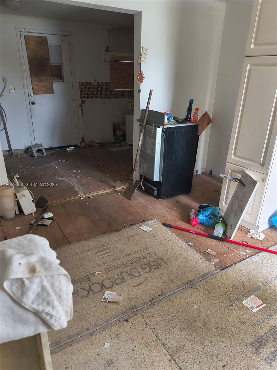 An unfinished kitchen features exposed subflooring, cement board underlayment, and a detached black appliance — 214 N 61st Ter, Hollywood FL 33024, HOLLYWOOD, FL