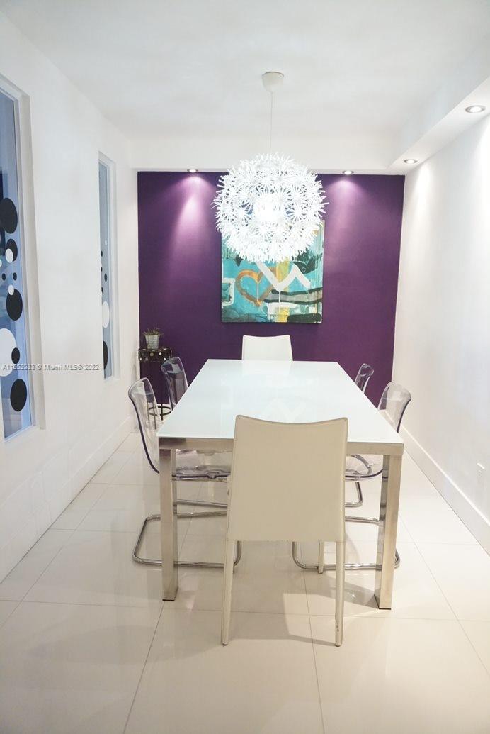 A dining room features a white table, clear chairs, and a purple accent wall — 5161 COLLINS AV # 309, Miami Beach FL 33140, MIAMI BEACH, FL