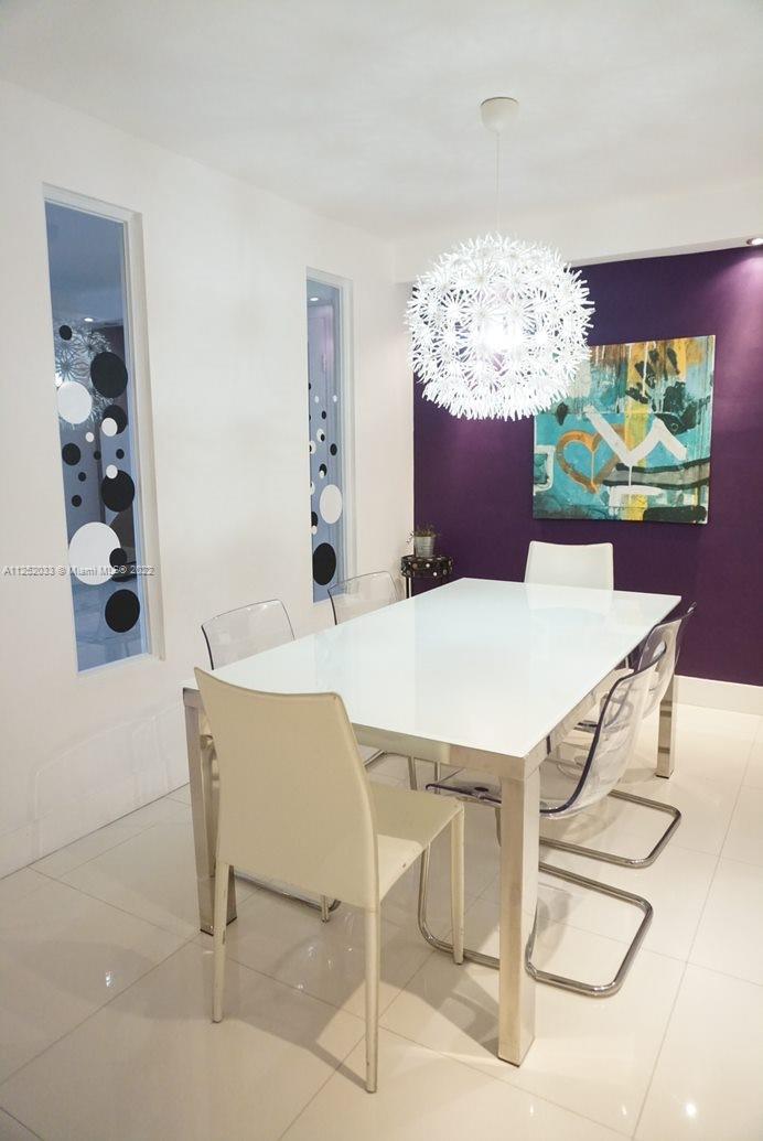 A dining room features a white table, clear chairs, a spiky pendant light, and purple wall — 5161 COLLINS AV # 309, Miami Beach FL 33140, MIAMI BEACH, FL