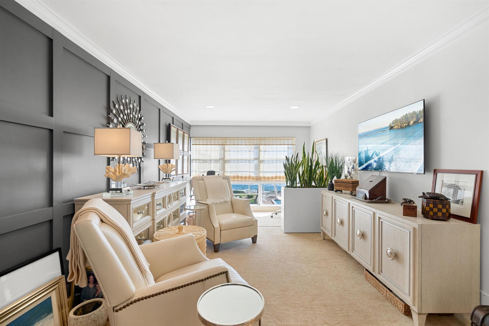 A living room features a dark paneled accent wall, two cream armchairs, and ocean views — 3851 N Ocean Boulevard # 308, Gulf Stream FL 33483, GULF STREAM, FL