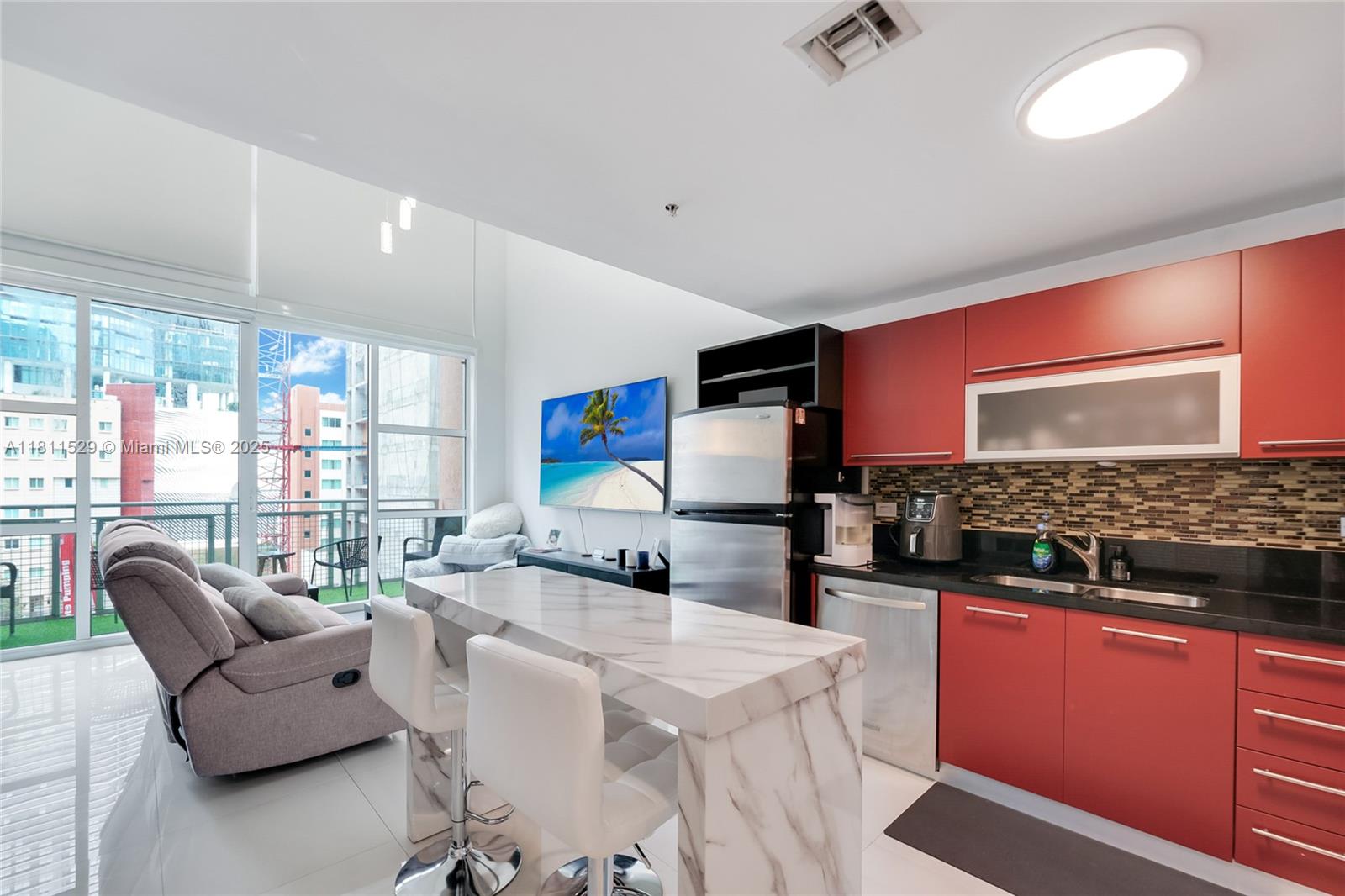 A modern studio apartment features a red kitchen, marble-topped island, and a balcony view — 244 Biscayne Blvd # 644, Miami FL 33132, MIAMI, FL