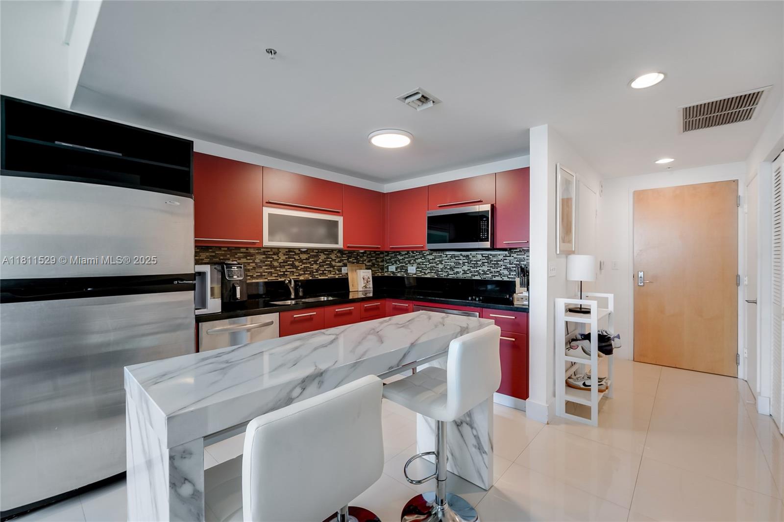 A kitchen features red cabinets, black countertops, a marble-topped island, and two white bar stools — 244 Biscayne Blvd # 644, Miami FL 33132, MIAMI, FL