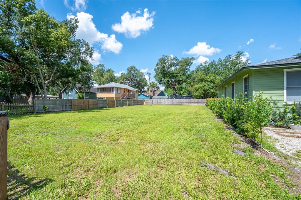 A large, grassy backyard features a wooden fence and a light green house exterior — 1010 ELM AVENUE, SANFORD, FL