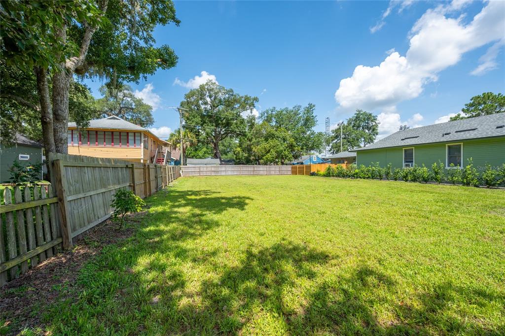 A grassy backyard is enclosed by a wooden fence between two neighboring houses — 1010 ELM AVENUE, SANFORD, FL