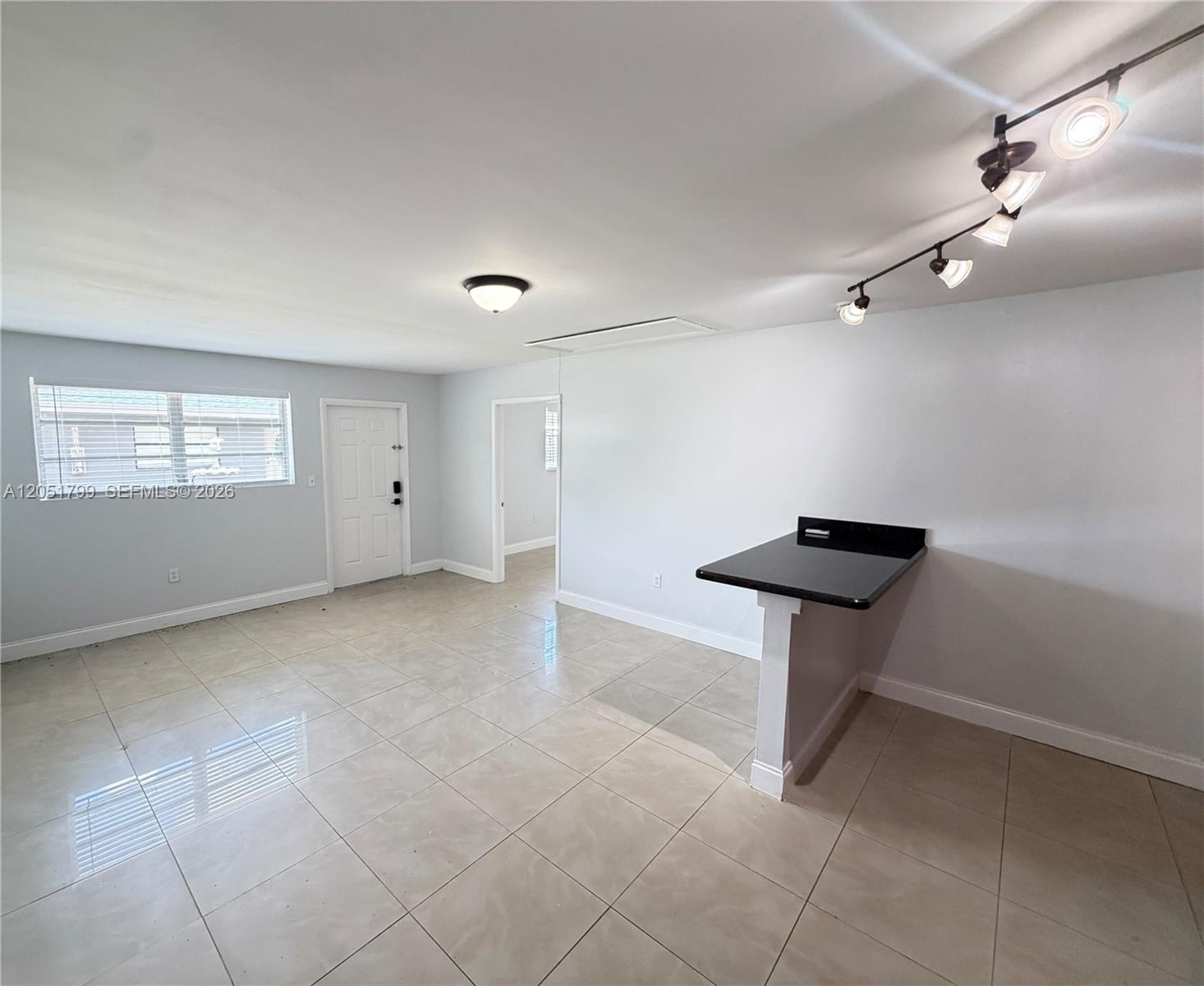 An open living area features light tile flooring, a breakfast bar, and track lighting — HOLLYWOOD, FL
