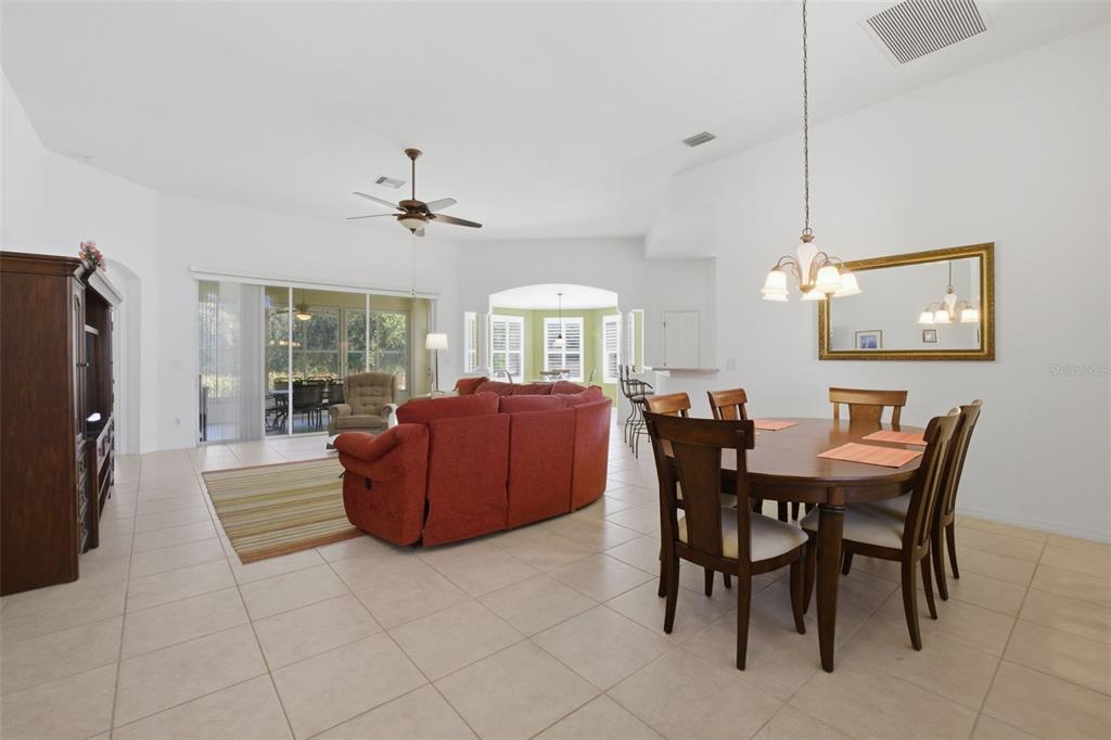 A spacious open-concept living and dining area with tile flooring and a large red sofa — 5922 SAGE LEAF PLACE, LEESBURG, FL