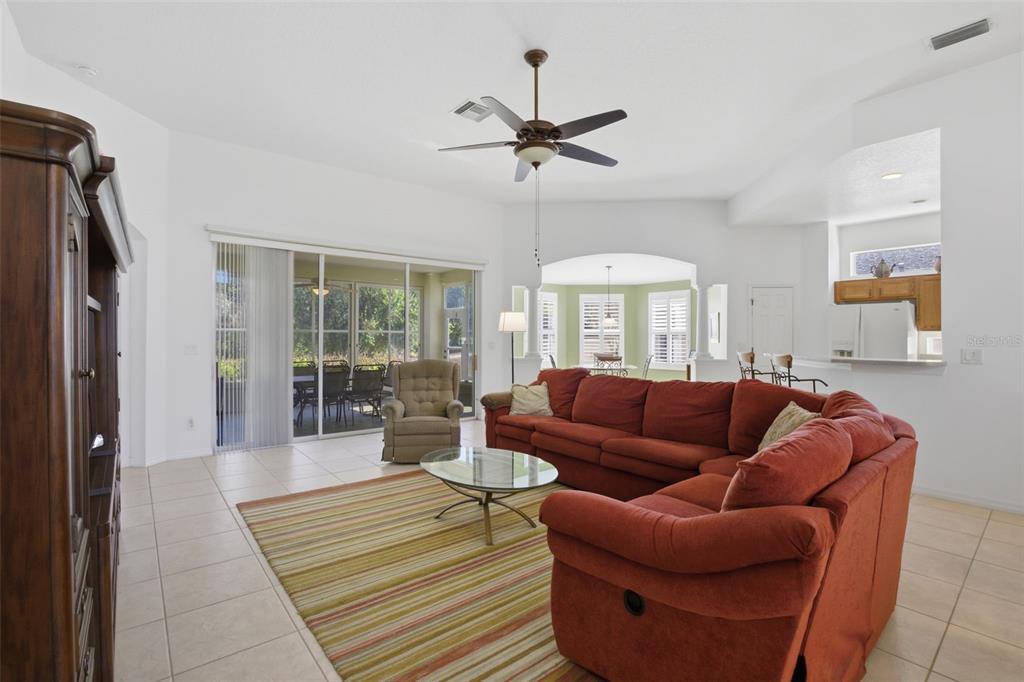 A living room with a red sectional sofa, glass coffee table, and sliding glass patio doors — 5922 SAGE LEAF PLACE, LEESBURG, FL