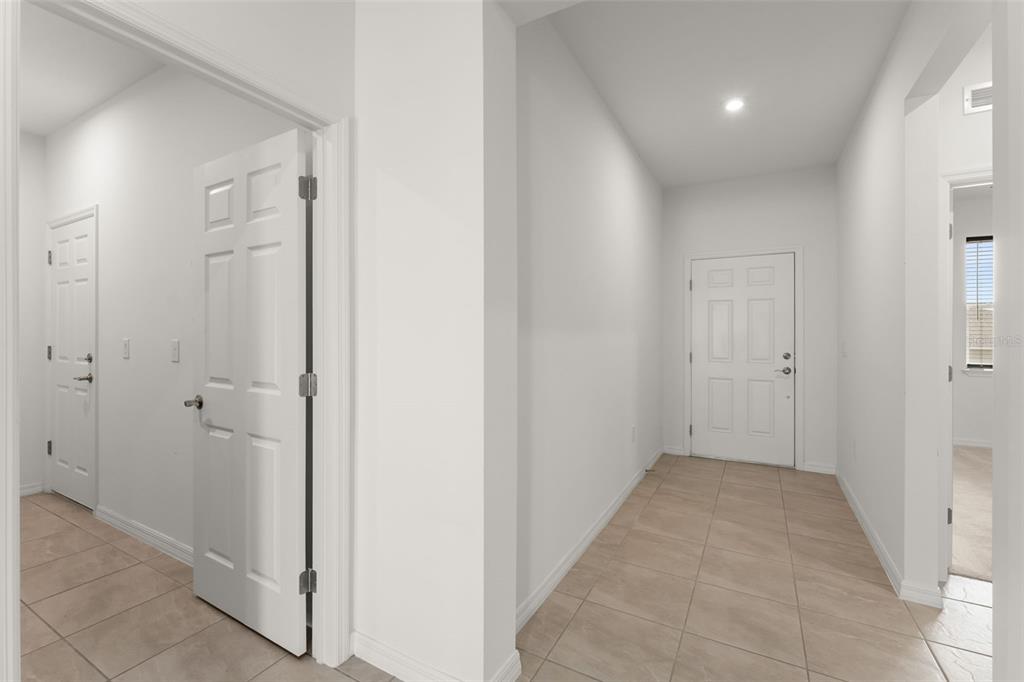 A bright entryway features light-colored tile flooring, white walls, and several interior doors — 1084 PATRIOT LOOP, HAINES CITY, FL