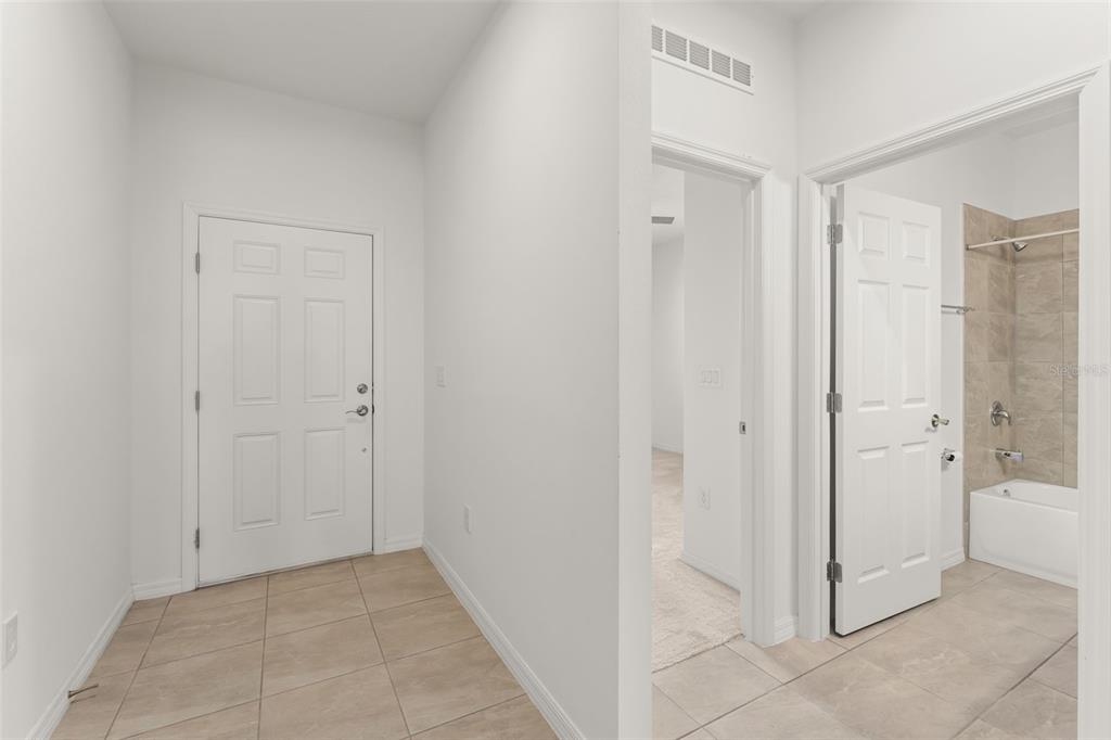 A tiled entryway leads to a white door, a carpeted room, and a tiled bathroom — 1084 PATRIOT LOOP, HAINES CITY, FL
