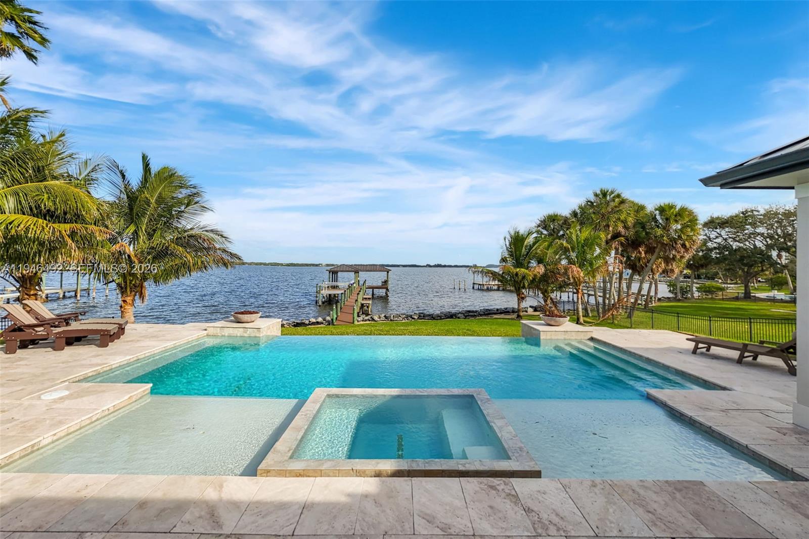 An infinity-edge pool and spa overlook a lake with a private dock and palm trees — 6275 N Highway 1, Melbourne FL 32940, MELBOURNE, FL